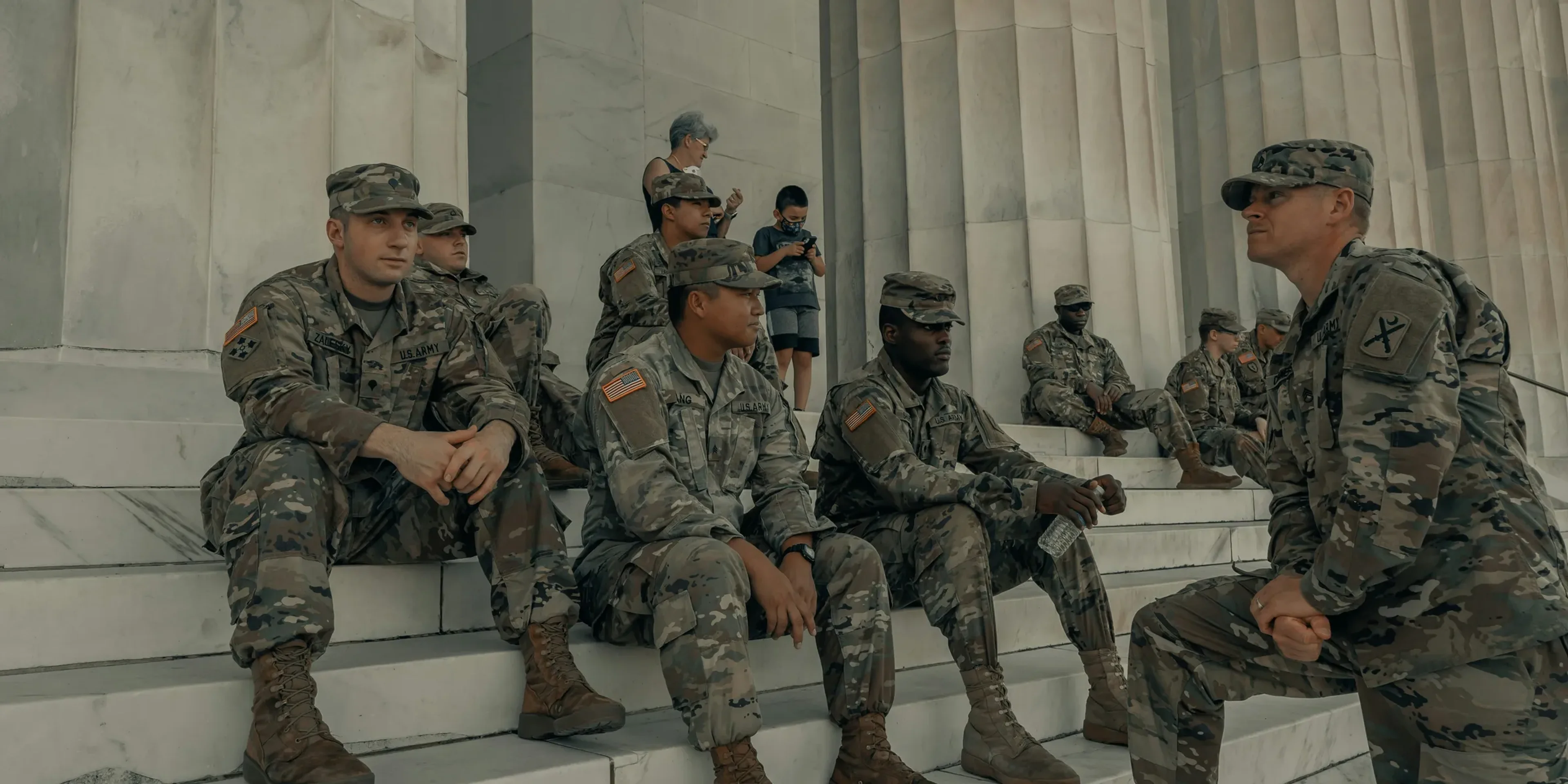 men in camouflage uniform standing near white wall