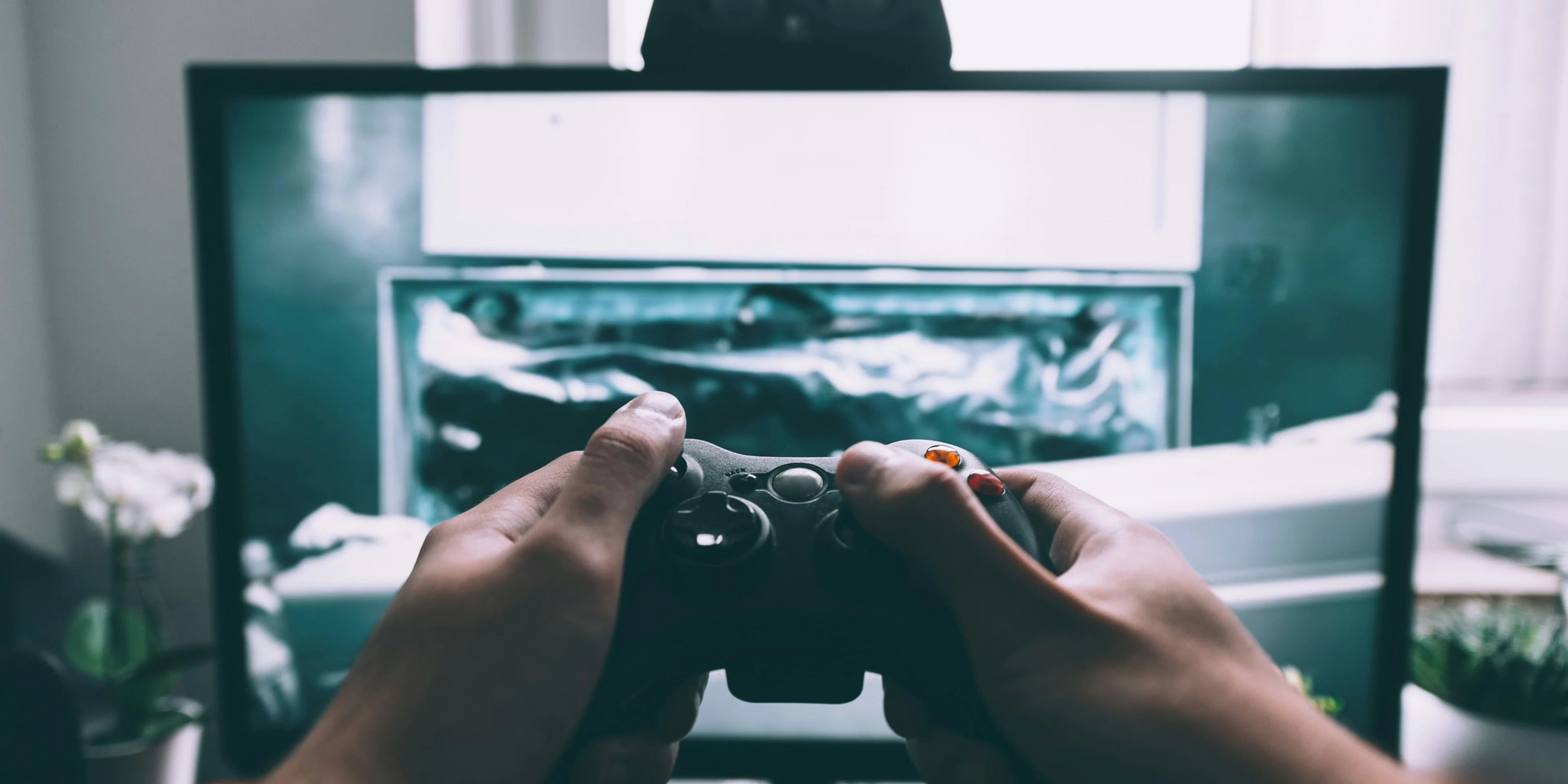 person holding game controller in-front of television.