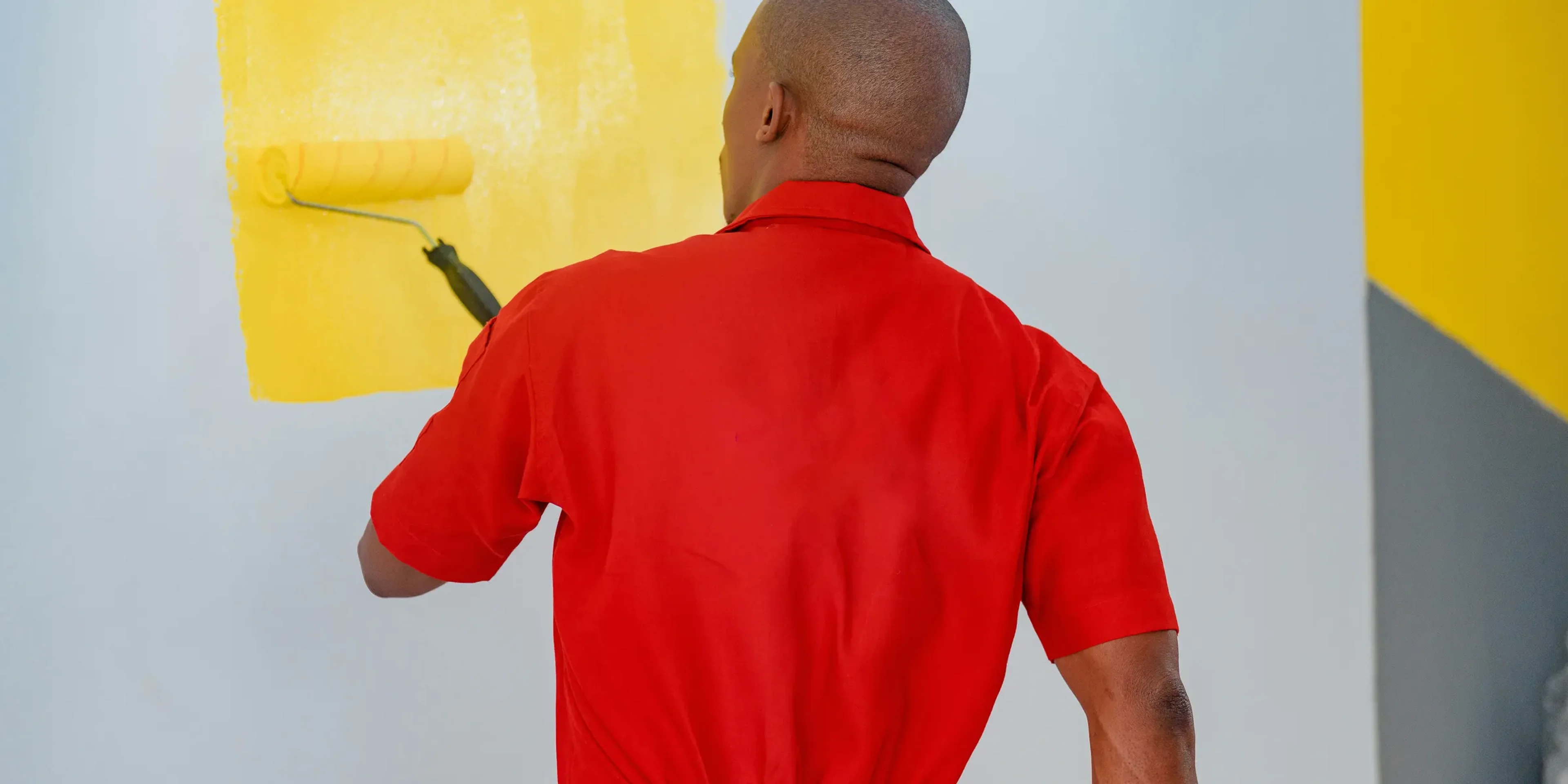a man painting a wall with yellow paint