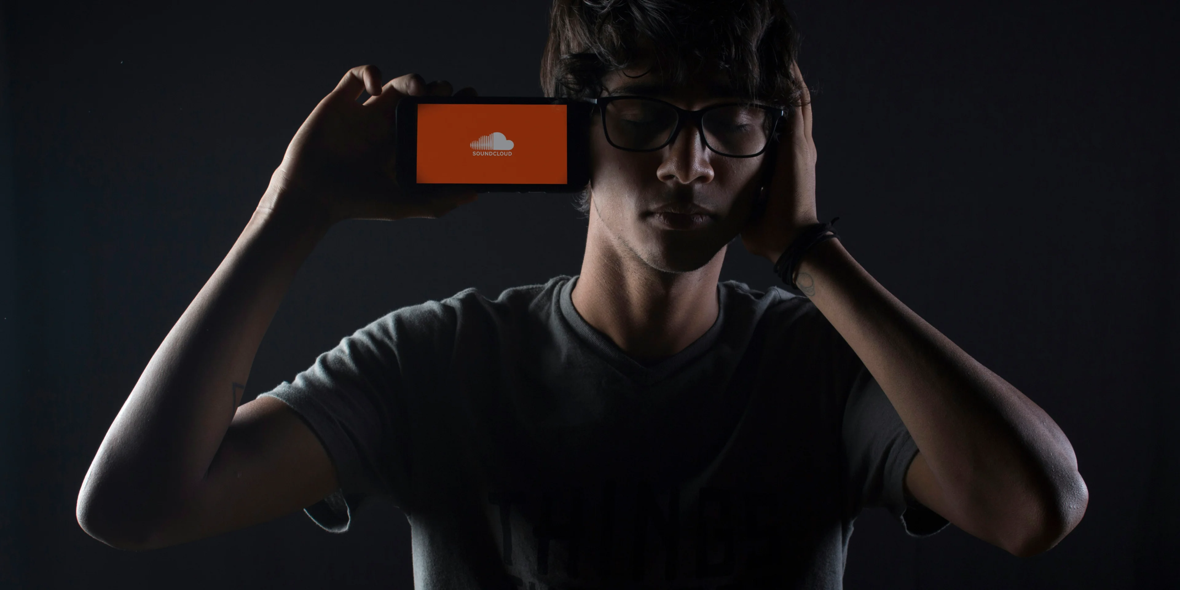 man listening to Soundcloud music on smartphone.