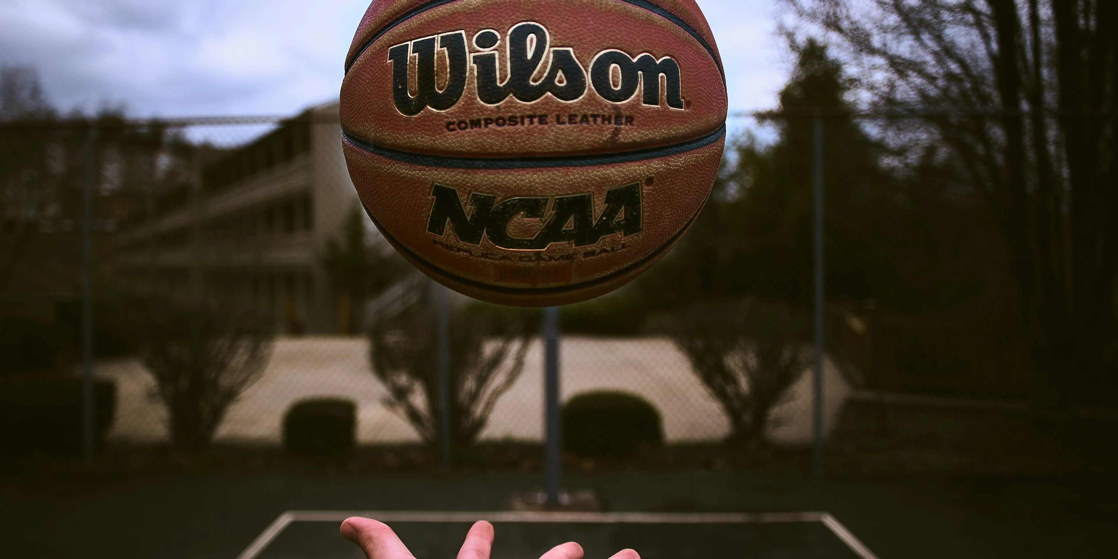 person releasing orange Wilson basketball ball