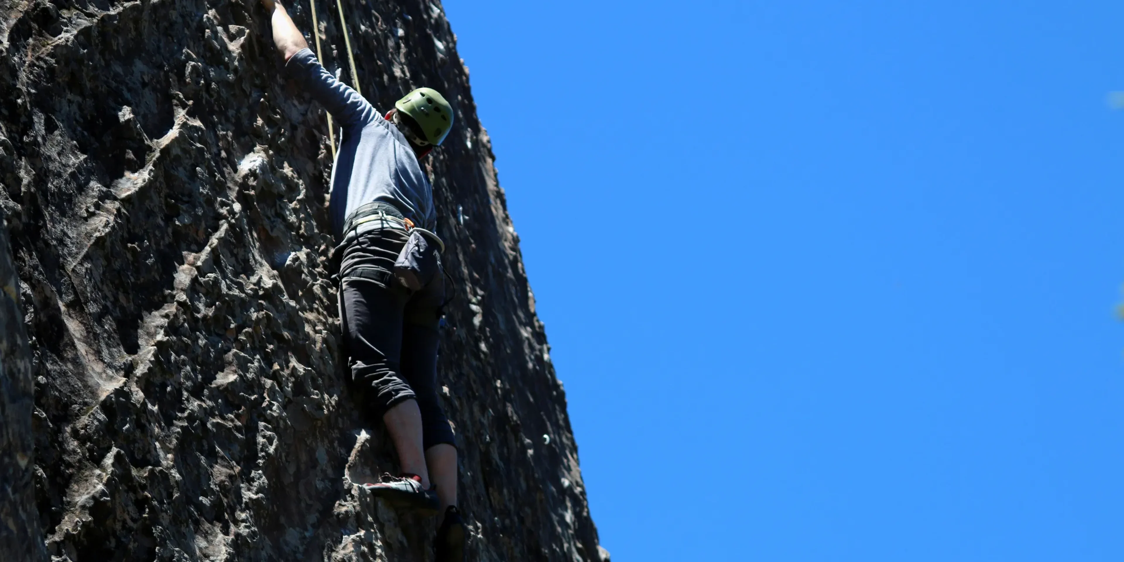man performing wall climbing under clear sky
