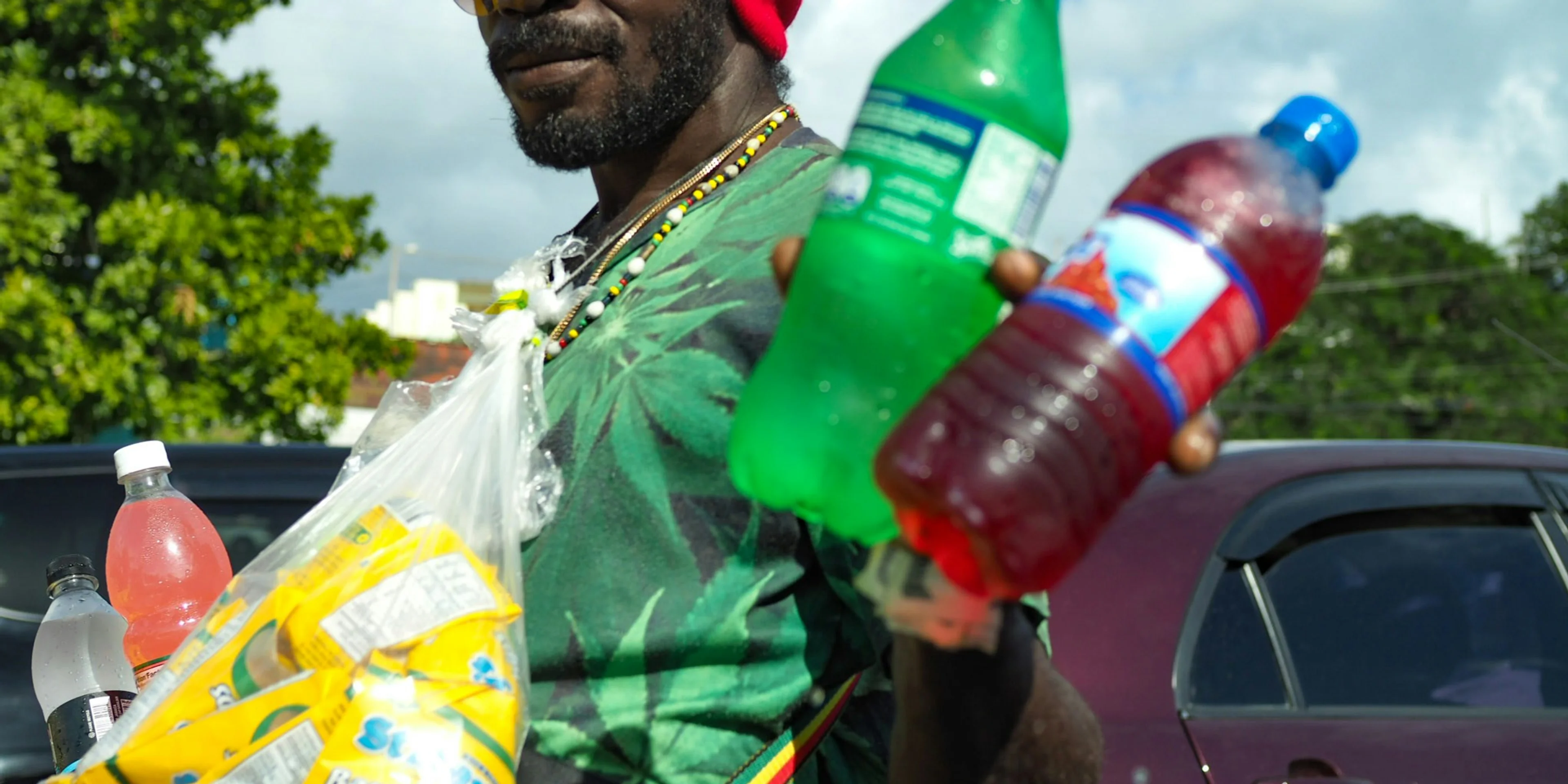 man wearing green t-shirt holding two Sprite and blue labeled bottles