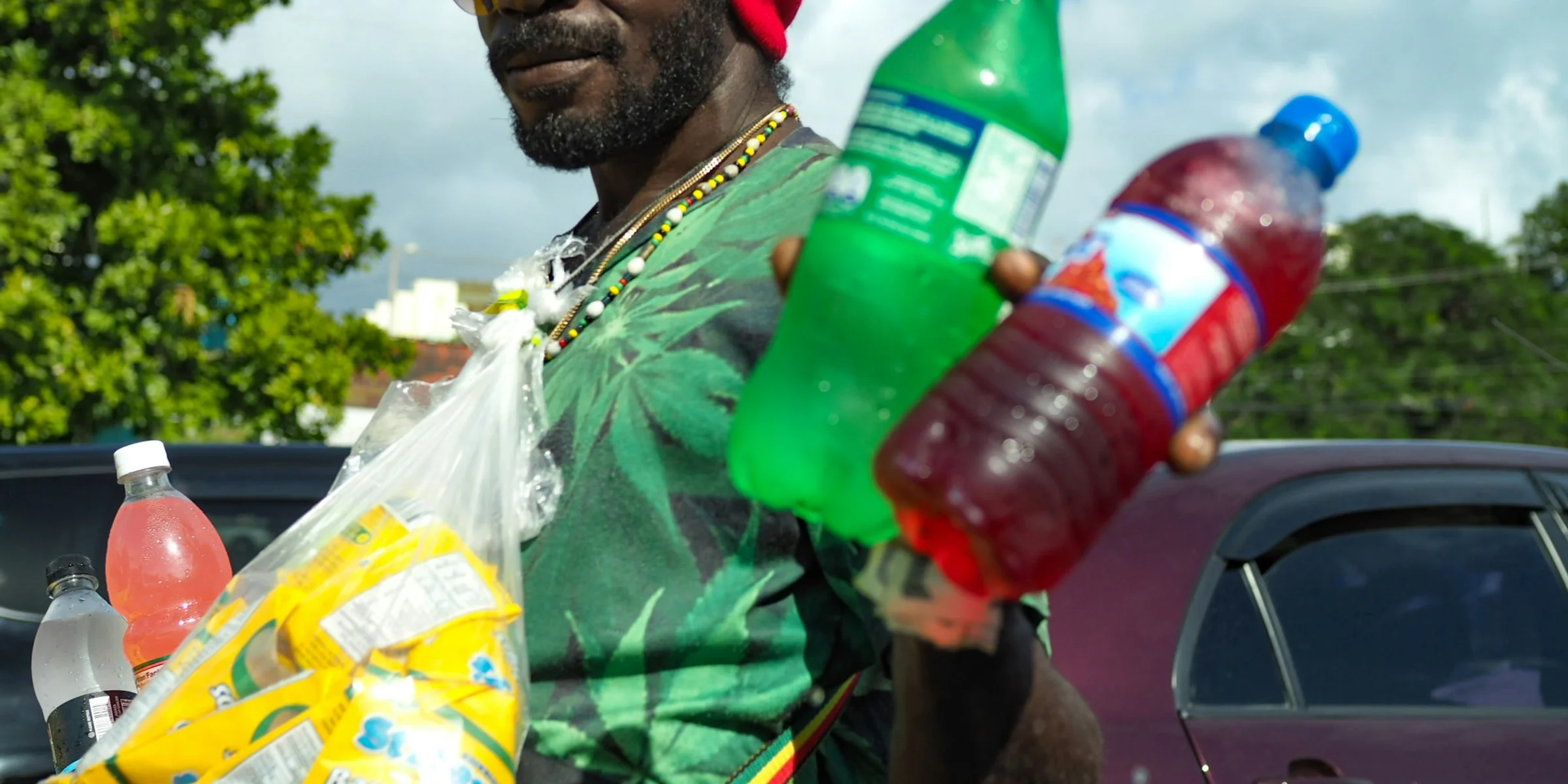 man wearing green t-shirt holding two Sprite and blue labeled bottles
