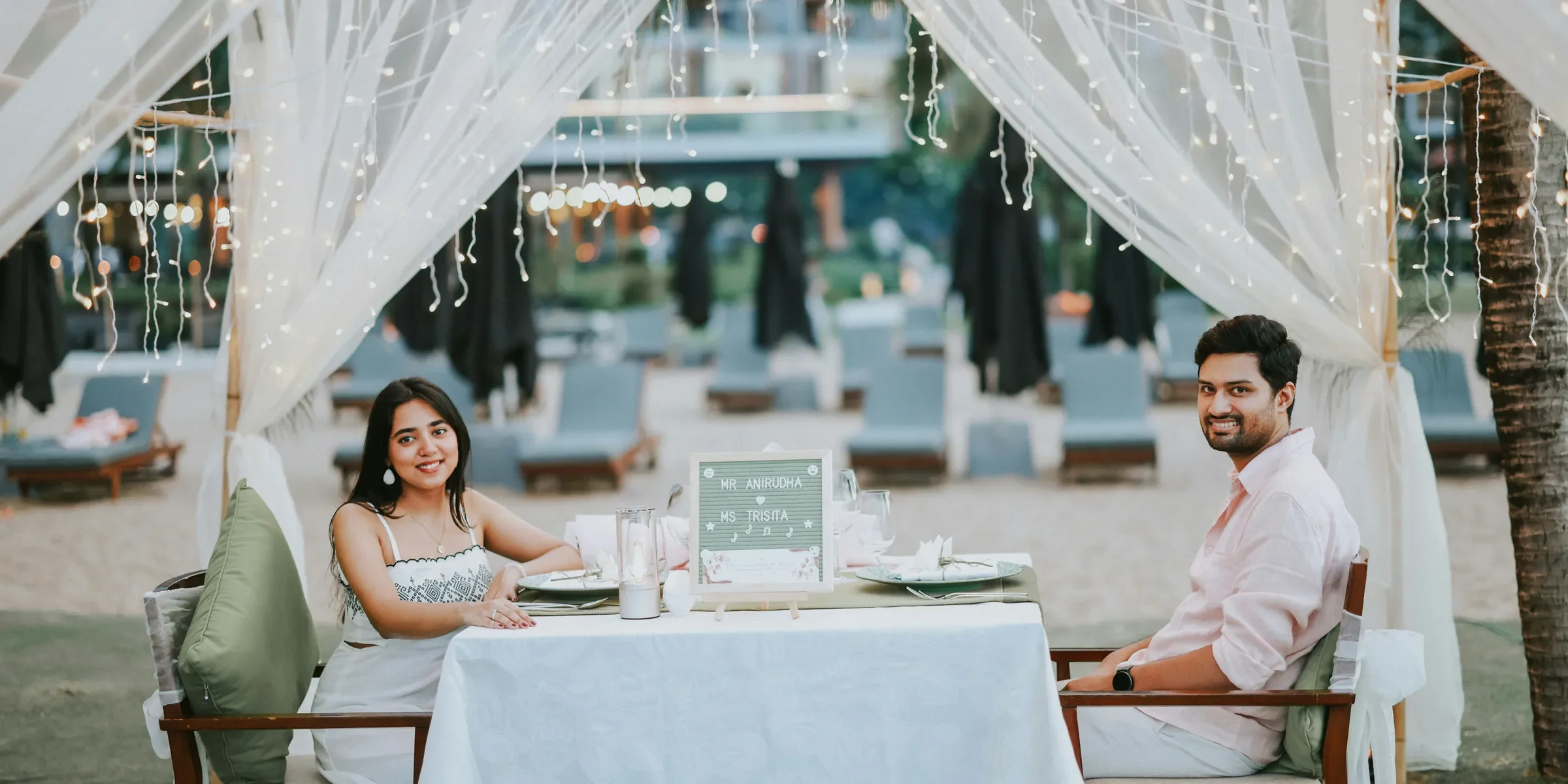 Couple having romantic dinner on beach under canopy lights