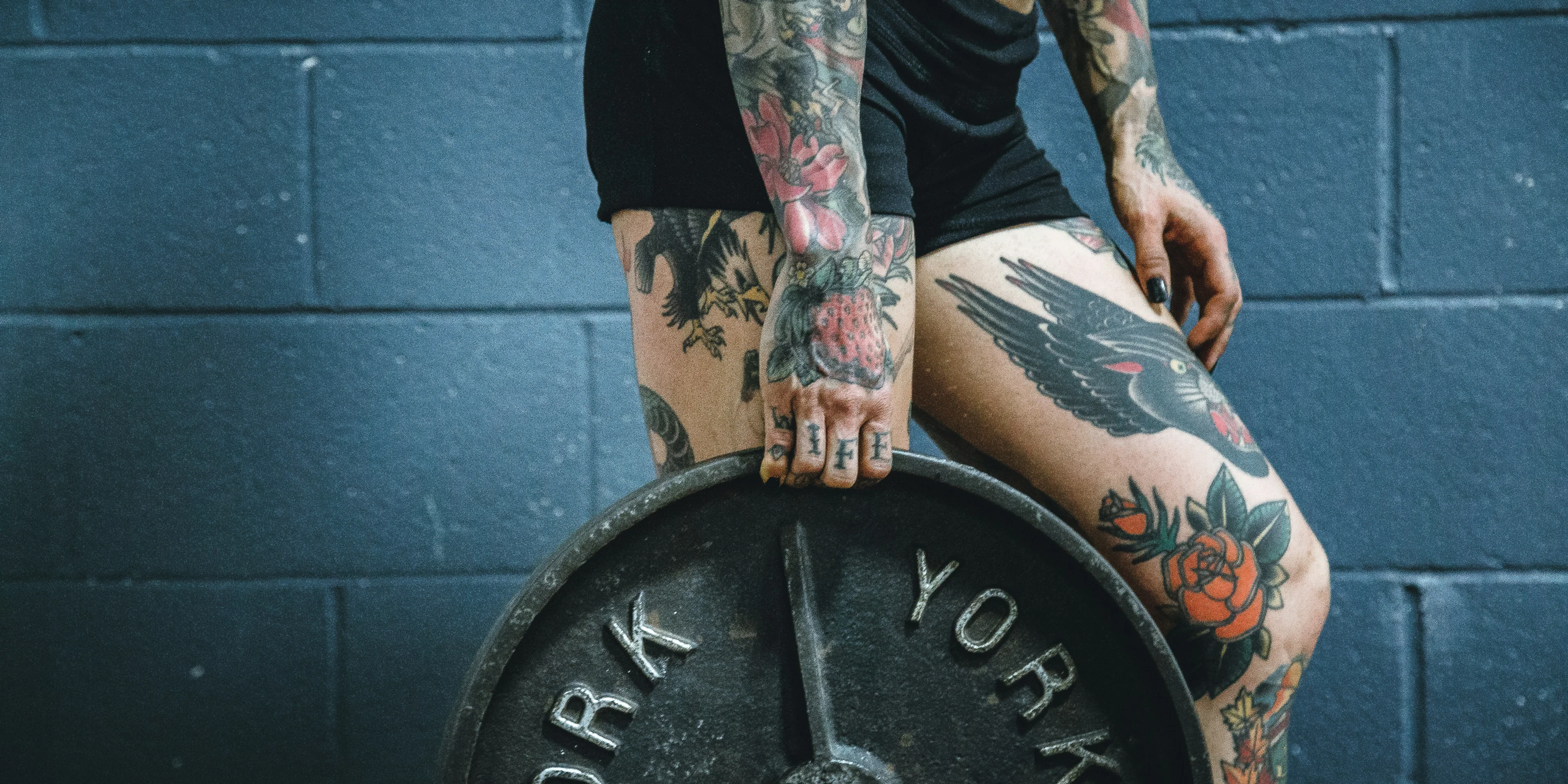 person carrying black weight plate with right hand.