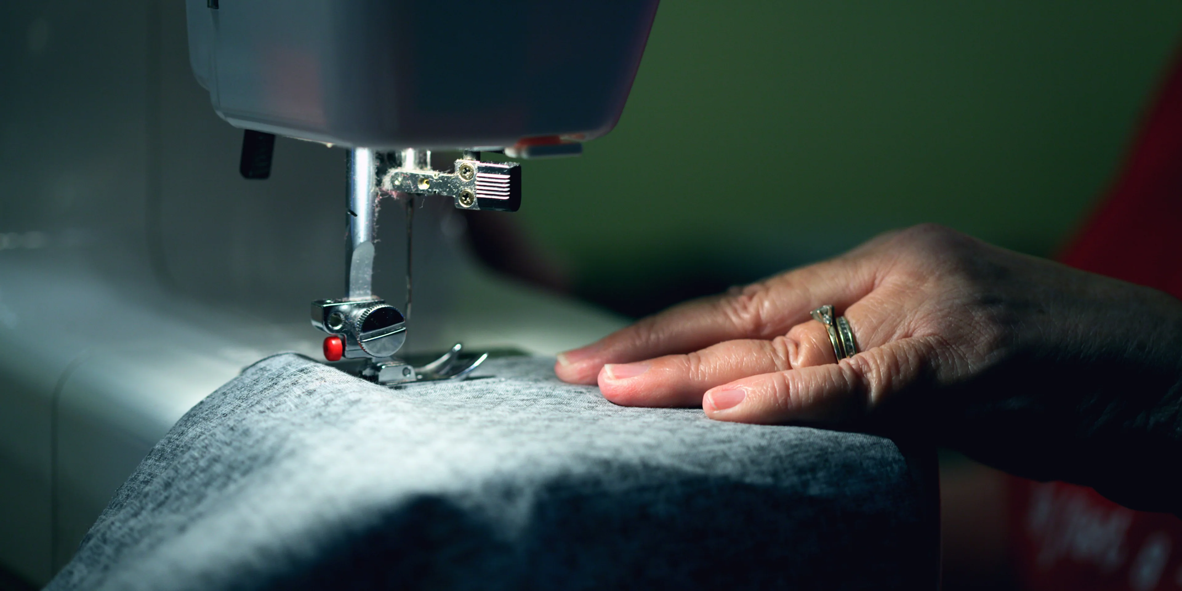 person in gray shirt sewing.