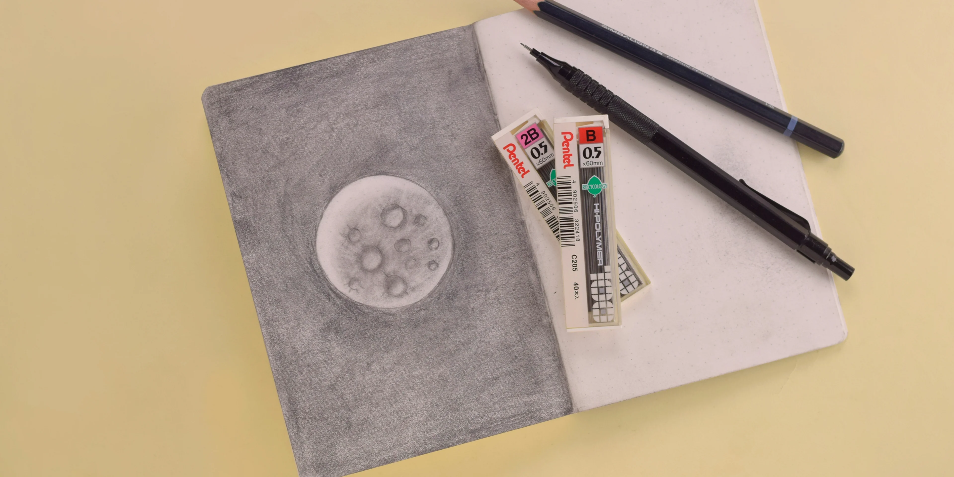 two pencils and two markers on a piece of paper.