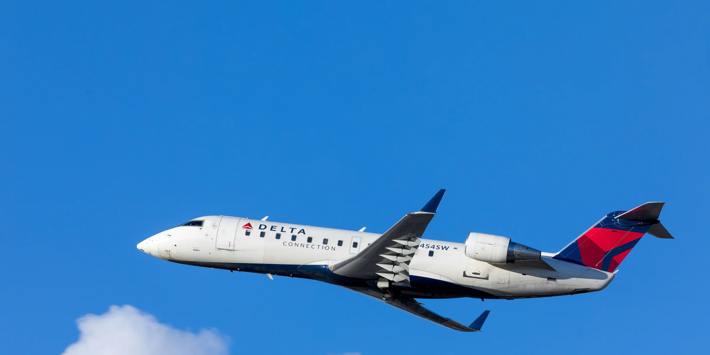 white, blue, and red Delta airways airliner on flight under white and blue cloudy sky.