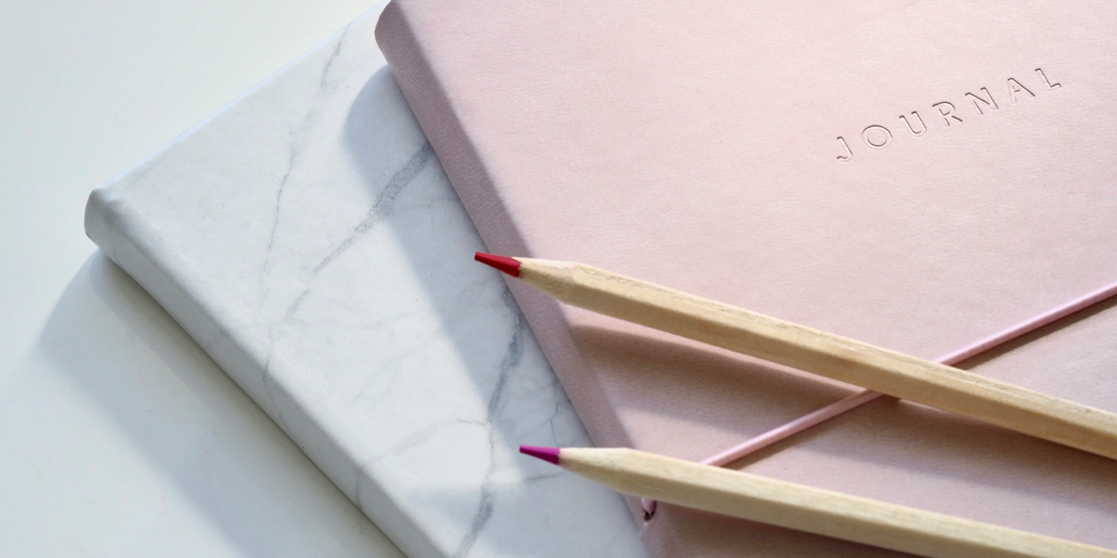 red and purple coloring pencils on pink journal.