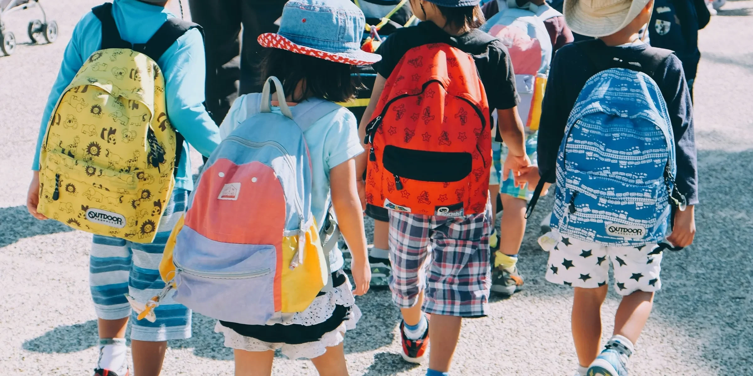 group of people wearing white and orange backpacks walking on gray concrete pavement during daytime
