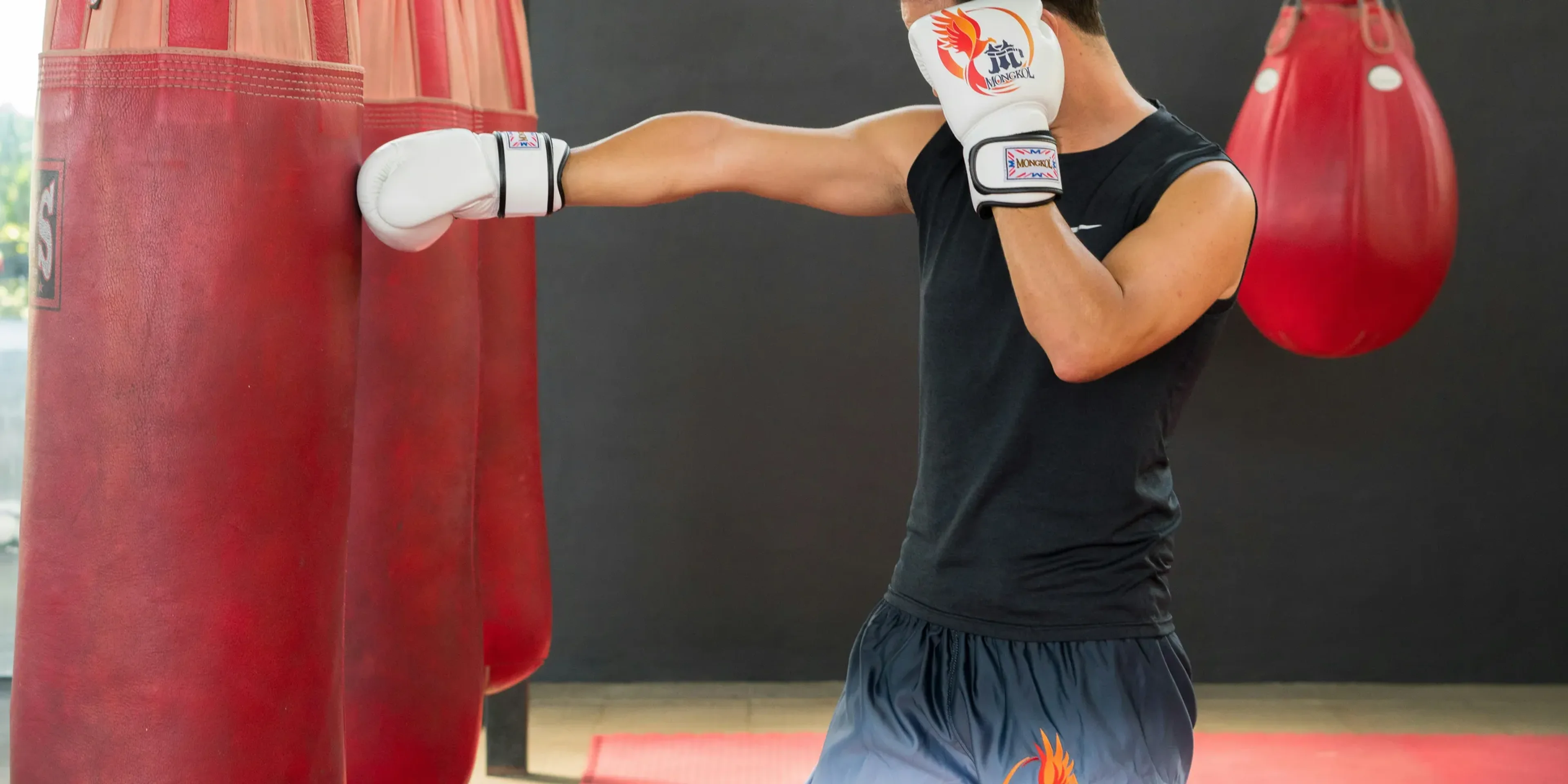 A woman in a boxing ring hitting a punching bag