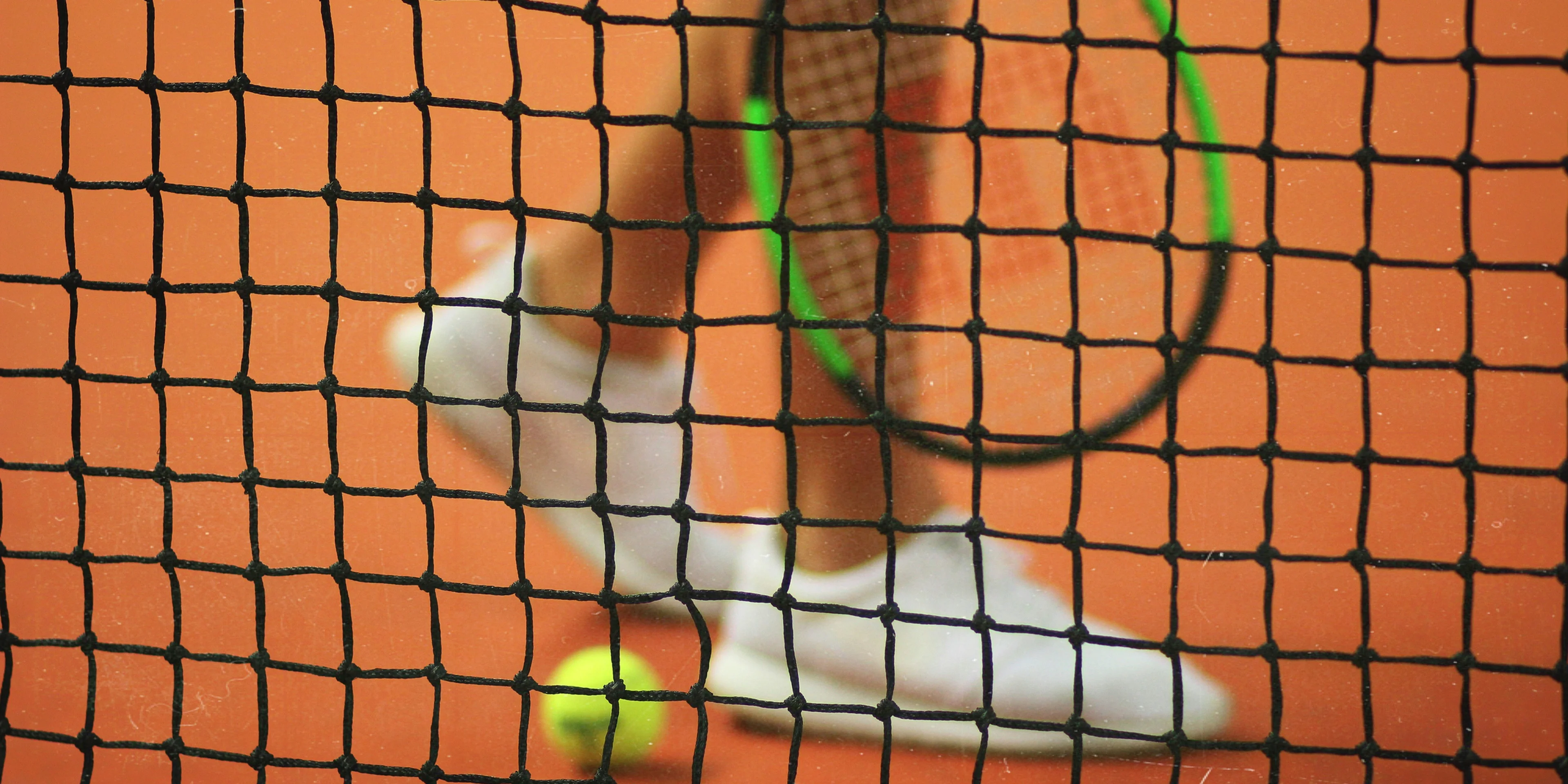 person wearing pair of white low-top sneakers while holding Wilson tennis racket