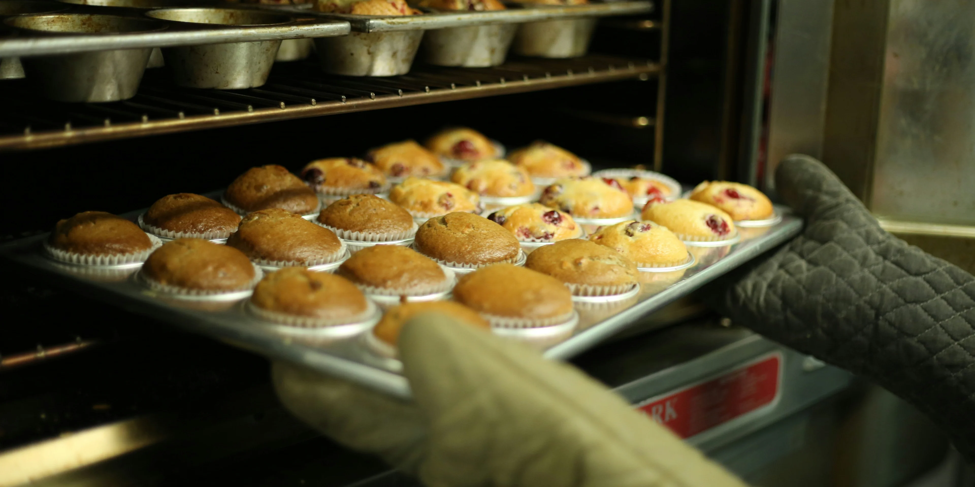 person holds tray of muffins on tray.