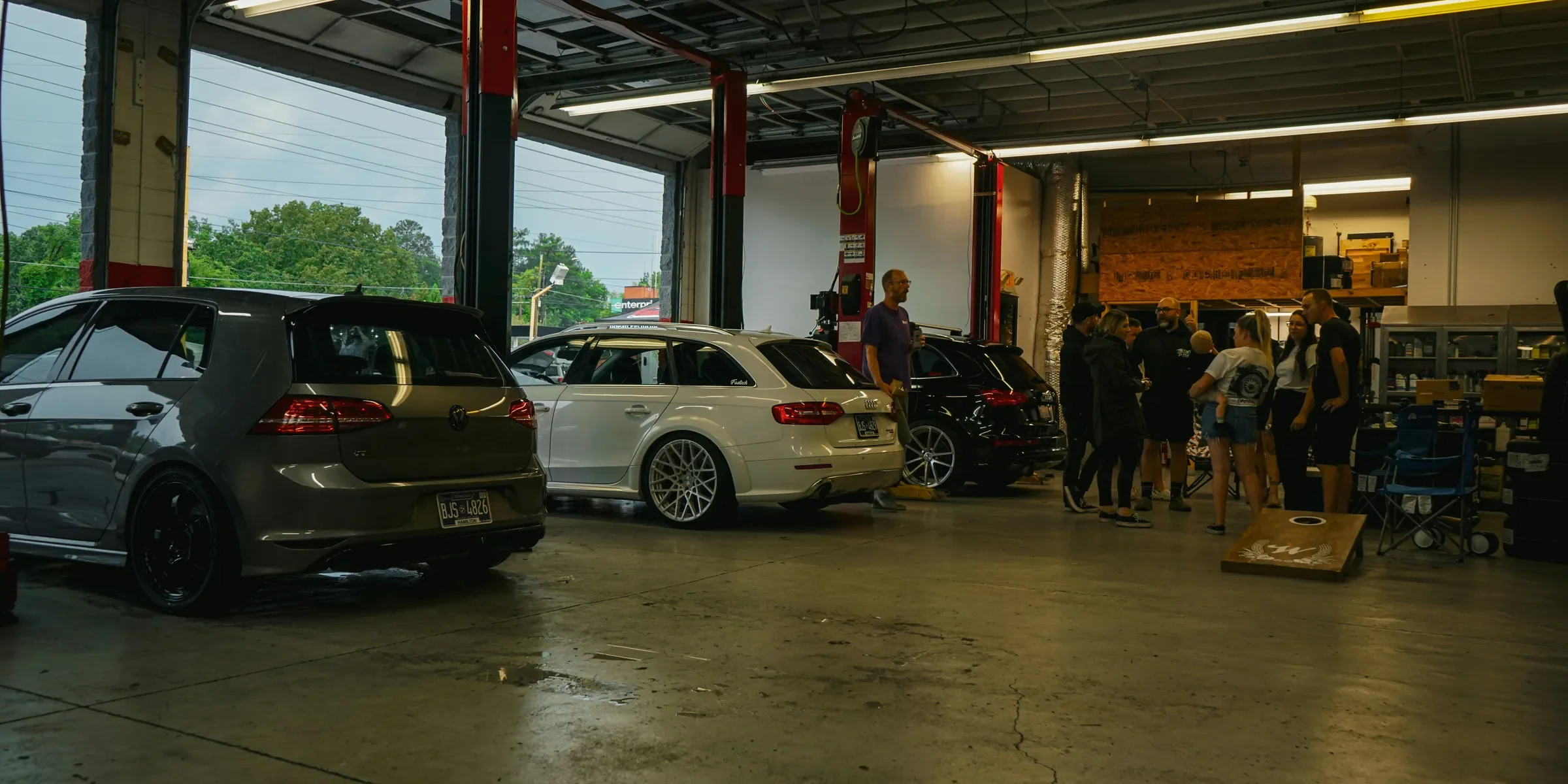 a group of people standing around a car in a garage