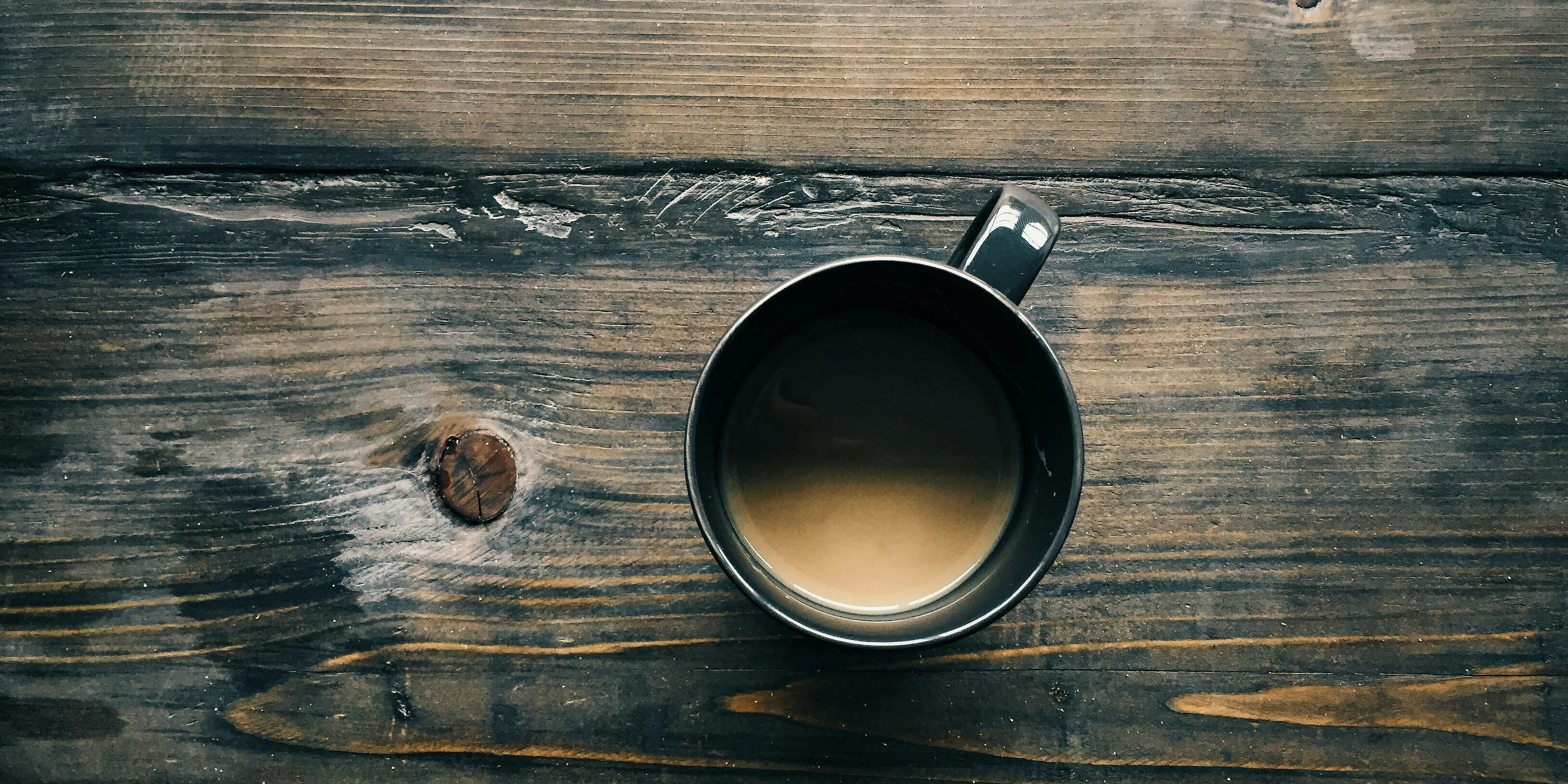 gray cup with brown liquid inside on top of table
