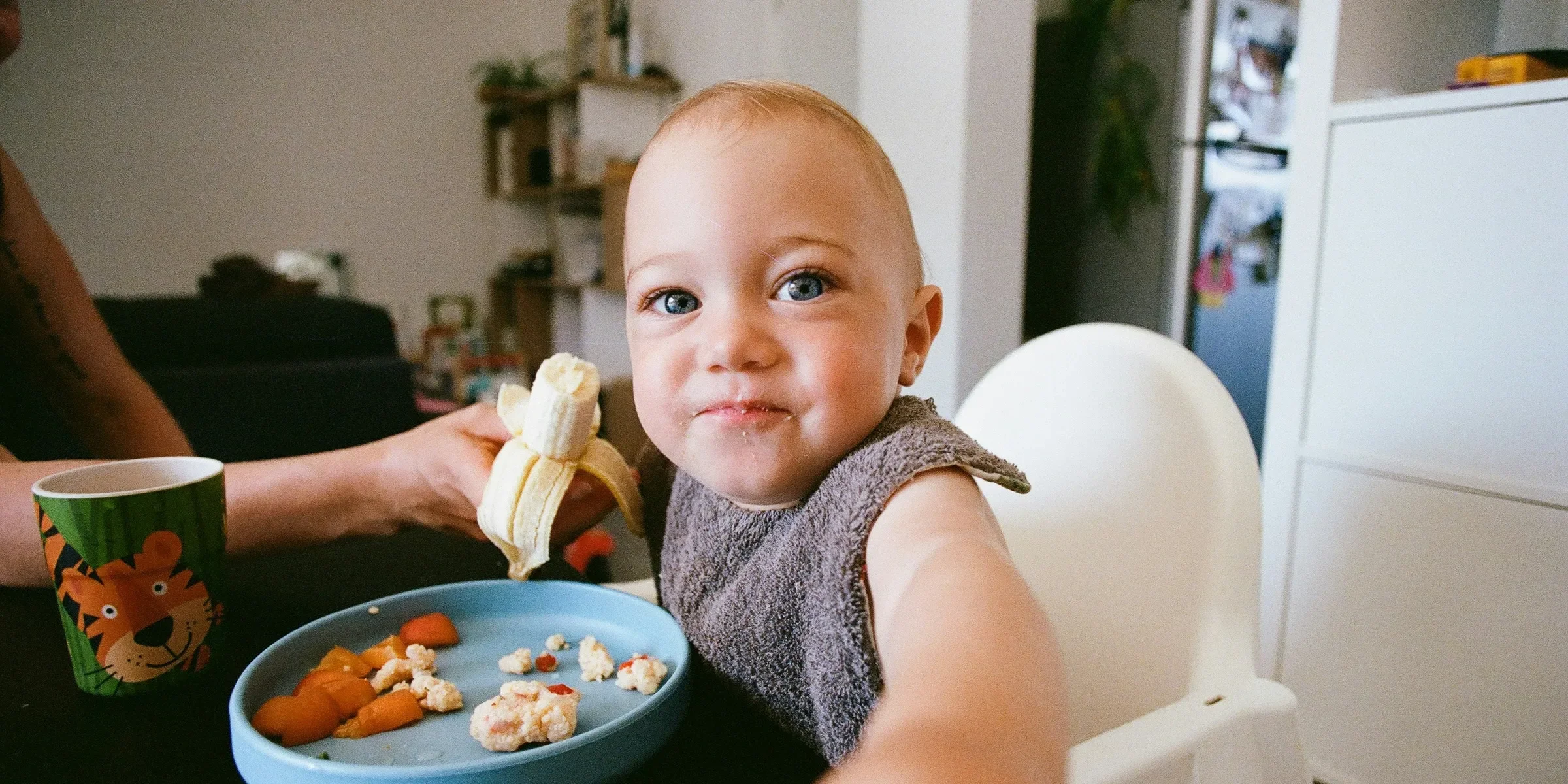 a baby sitting at a table with a plate of food