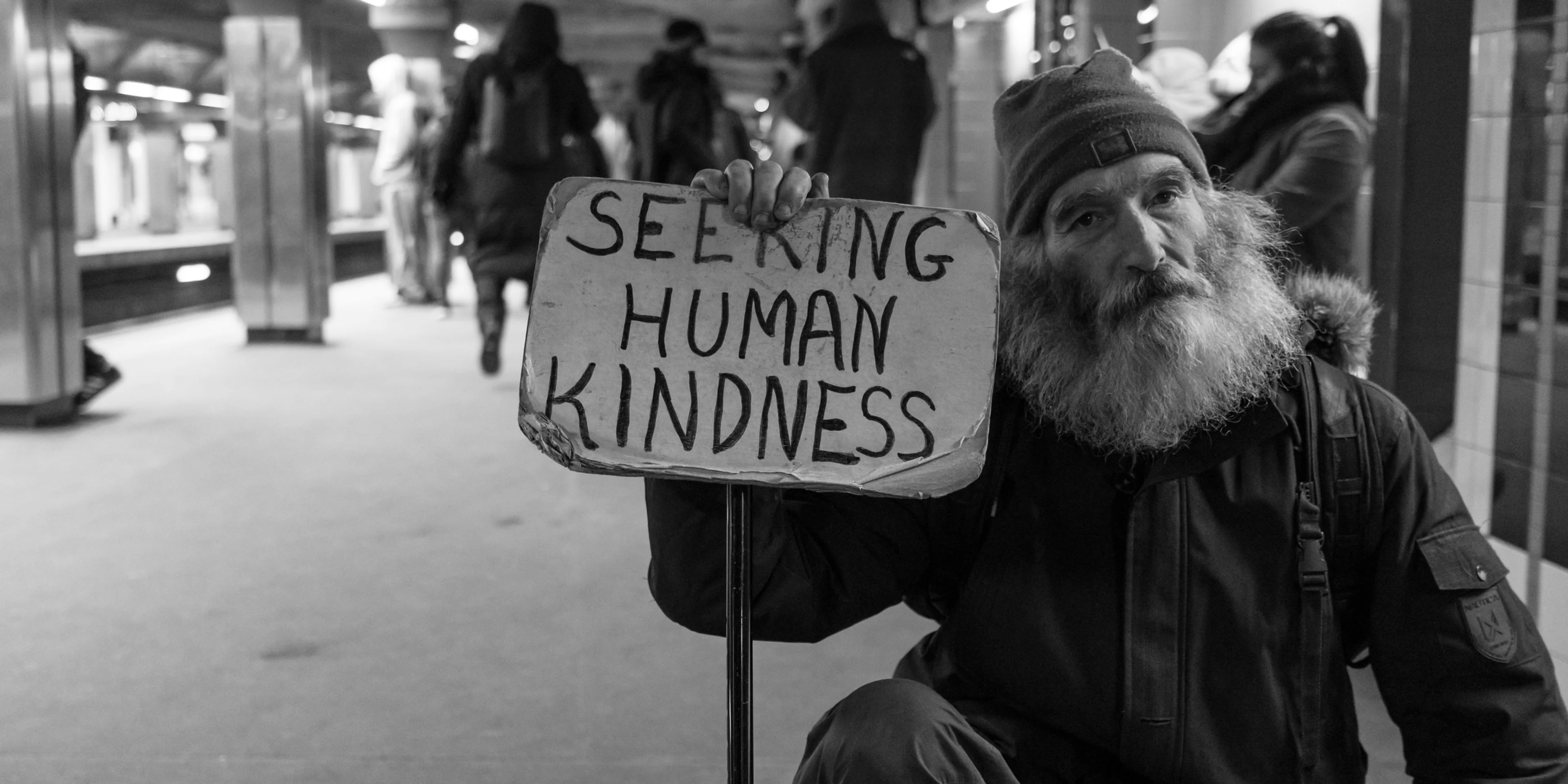 man holding card with seeking human kindness text.