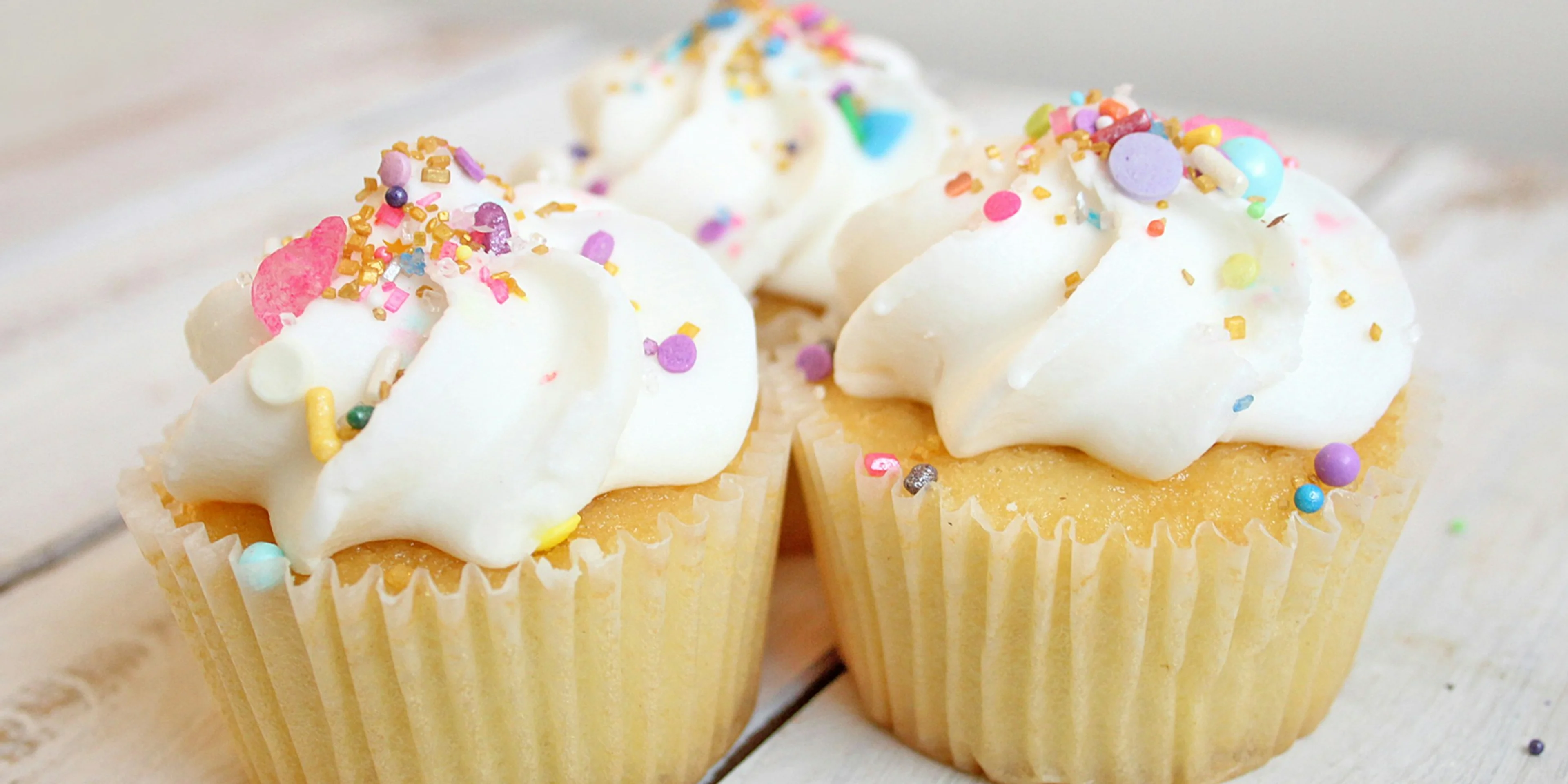 three cupcakes on white wood.