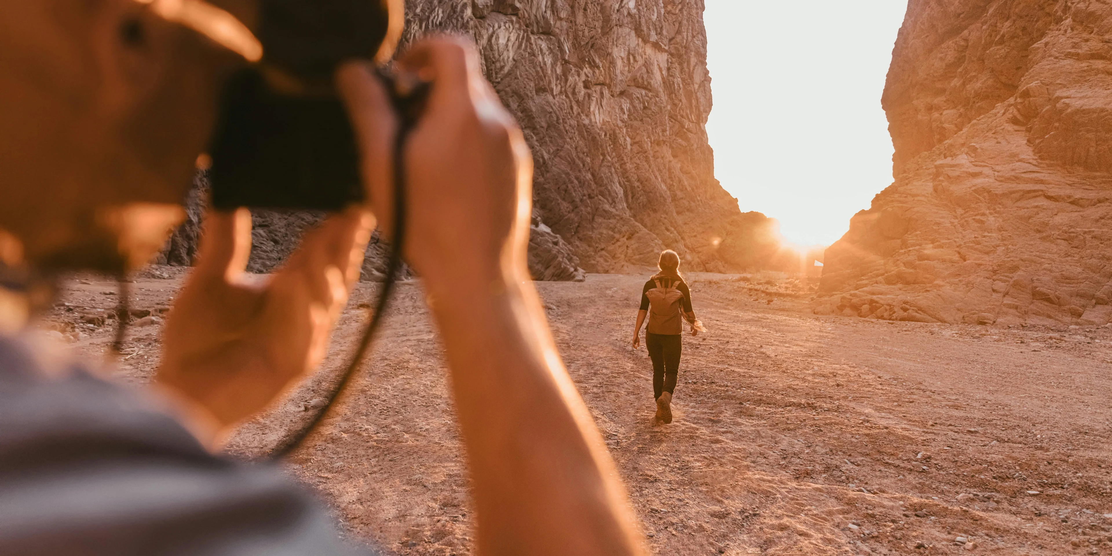 a man taking a picture of a woman in the desert
