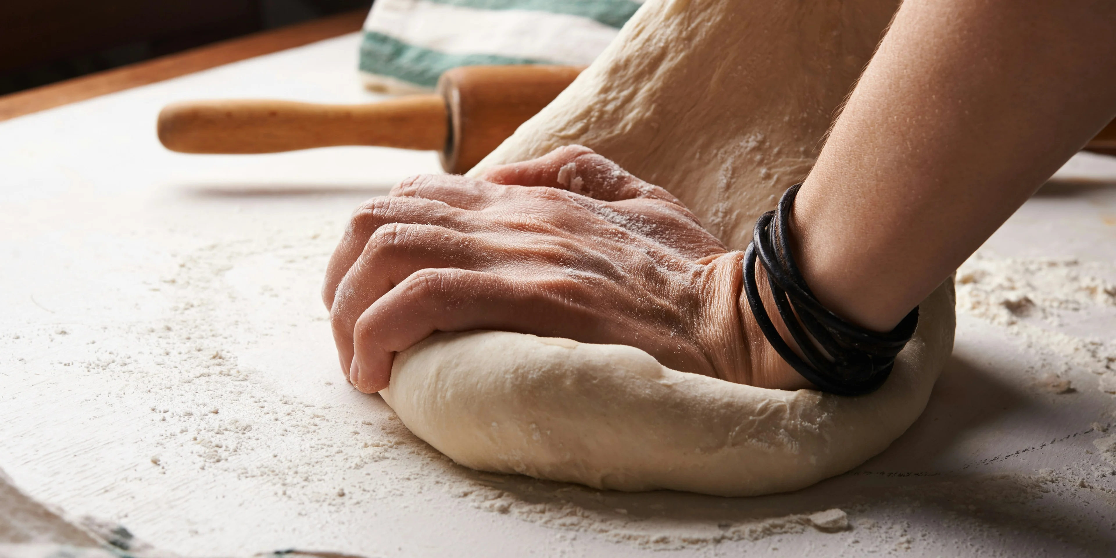 person making dough beside brown wooden rolling pin
