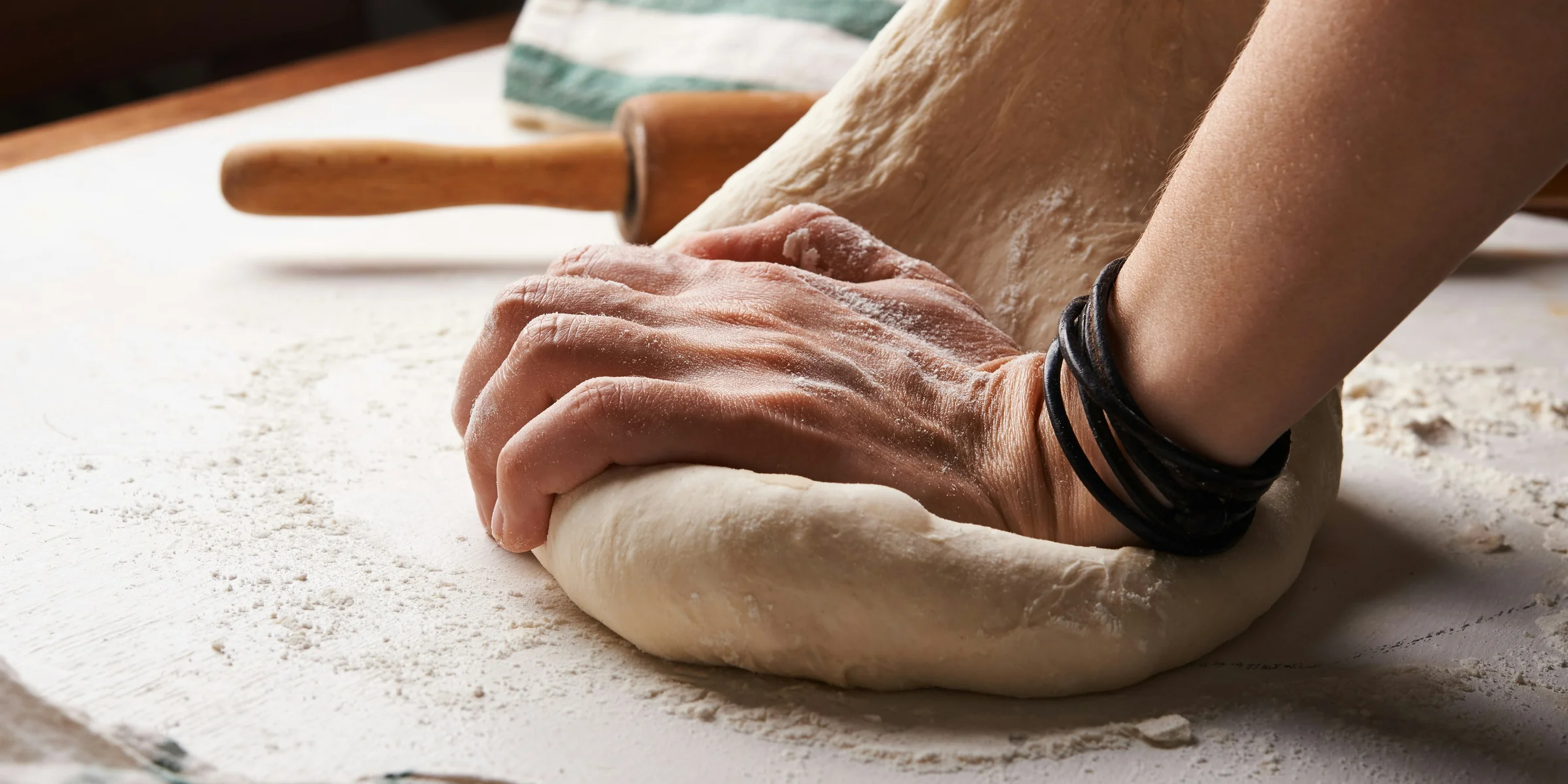 person making dough beside brown wooden rolling pin