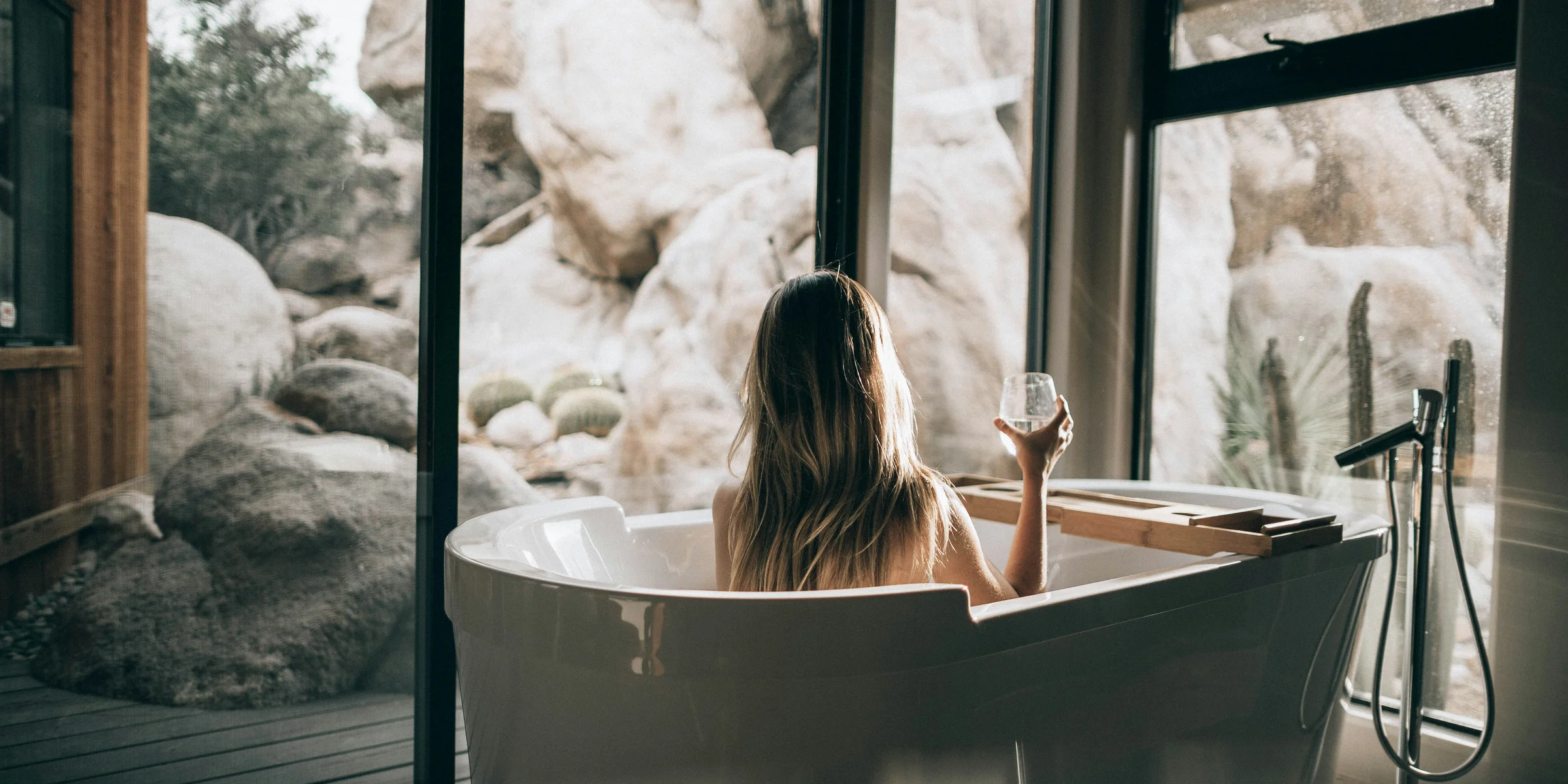 woman in white bathtub holding clear drinking glass