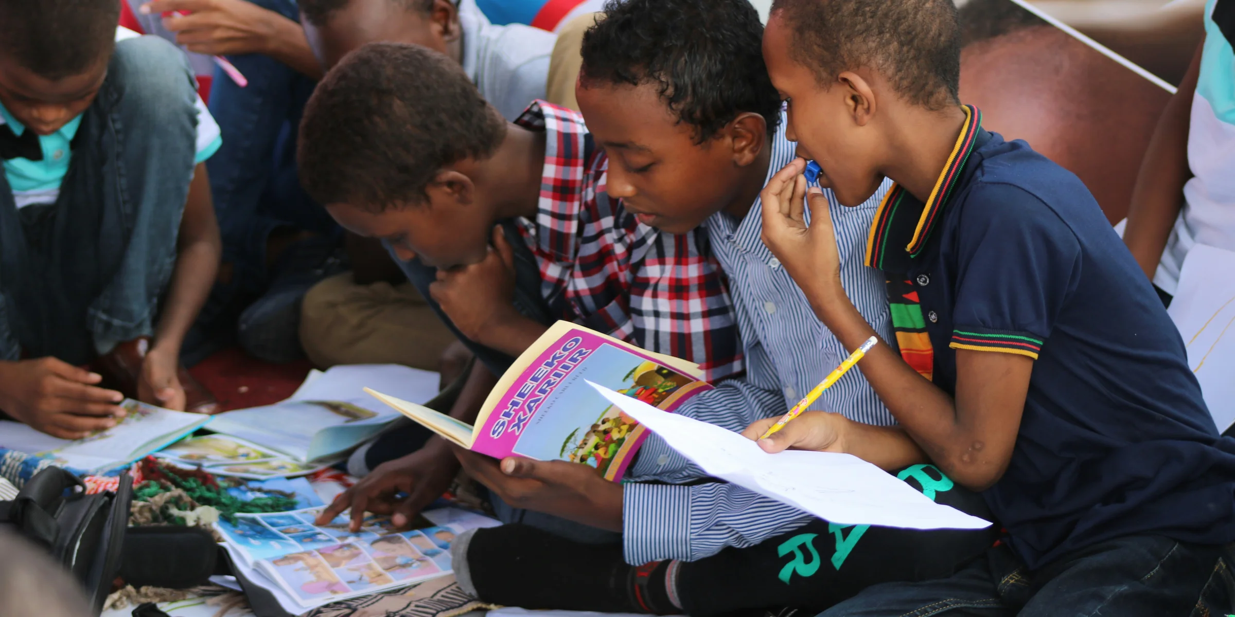 boy in blue and white plaid shirt reading book.