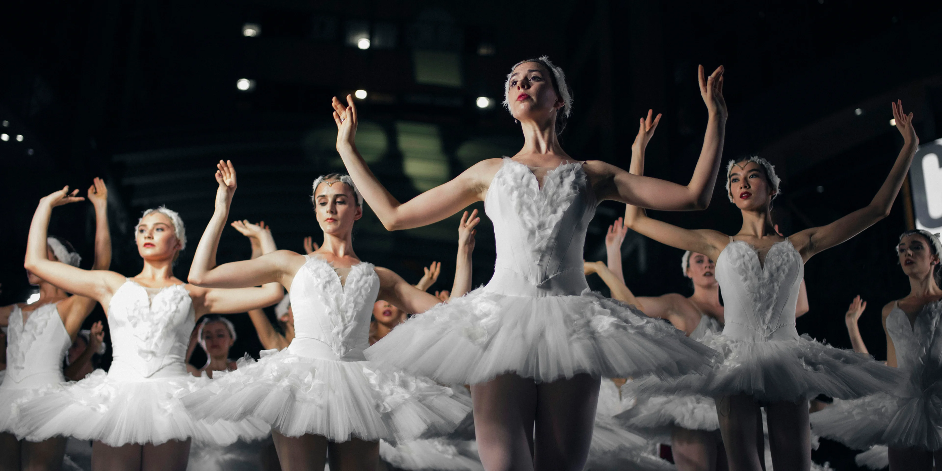 group of ballerinas dancing while raising both hands