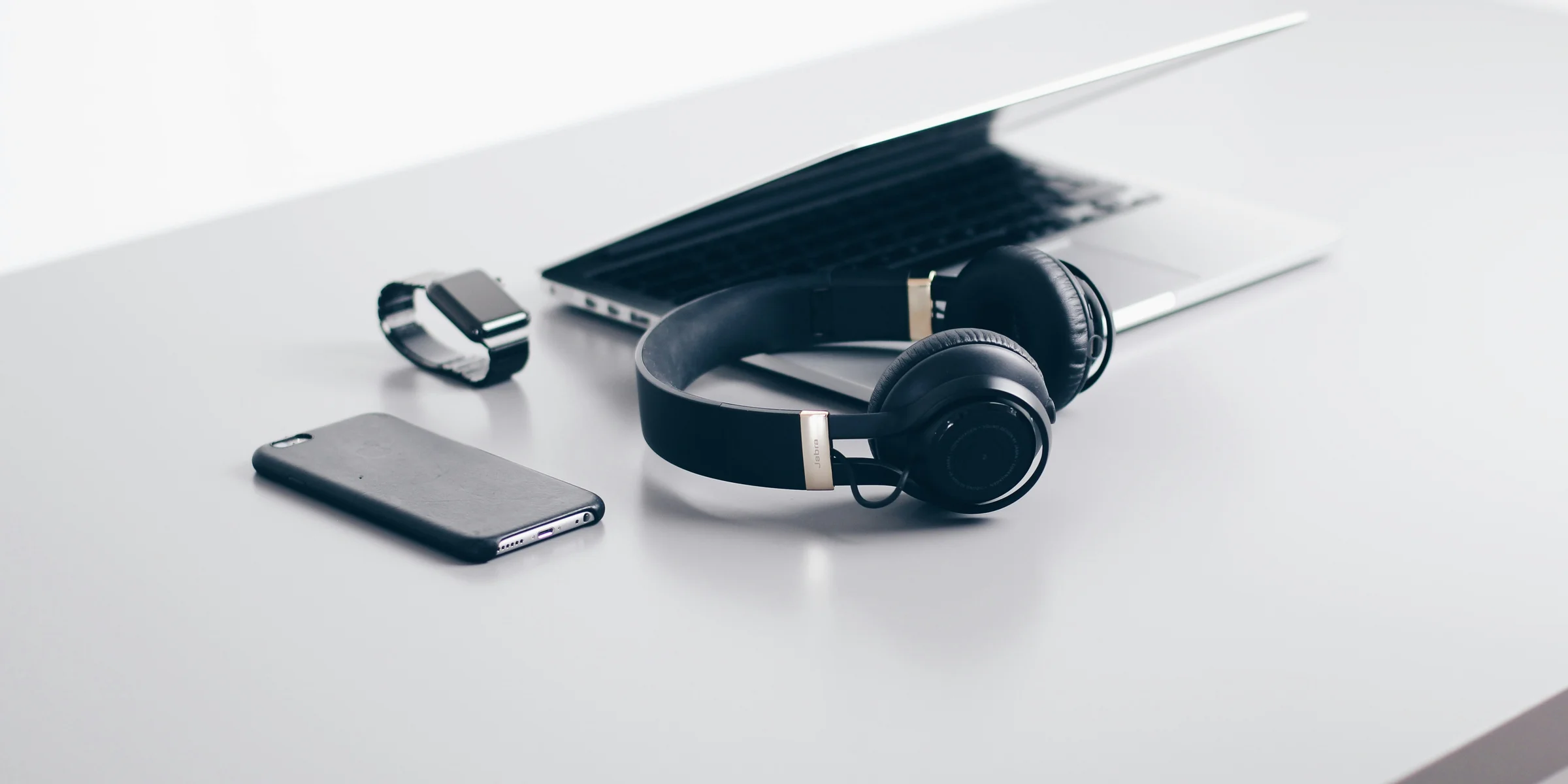 black cordless headphones beside closed black laptop computer and smartphone