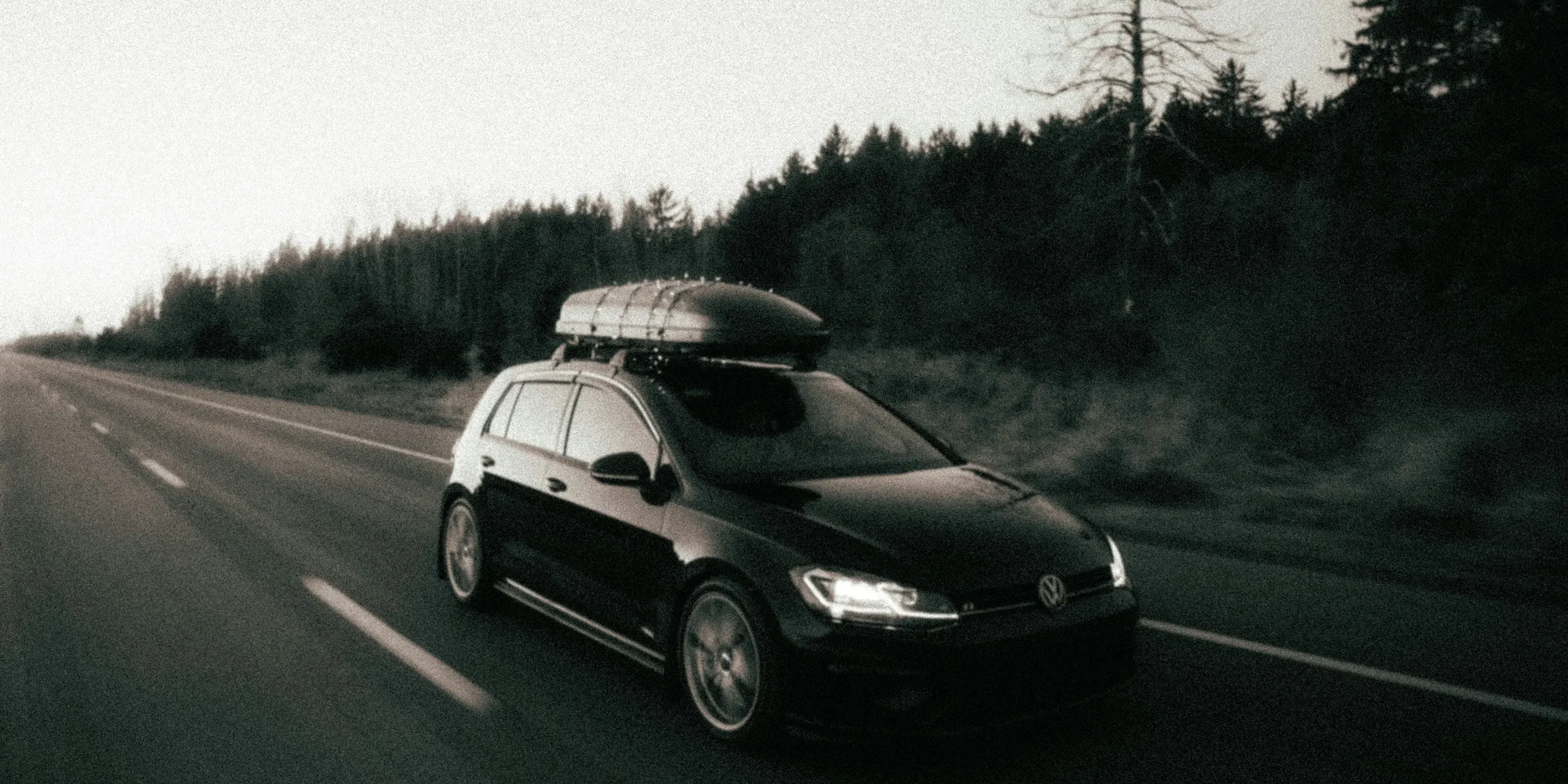 a car driving down a road with a surfboard on top of it
