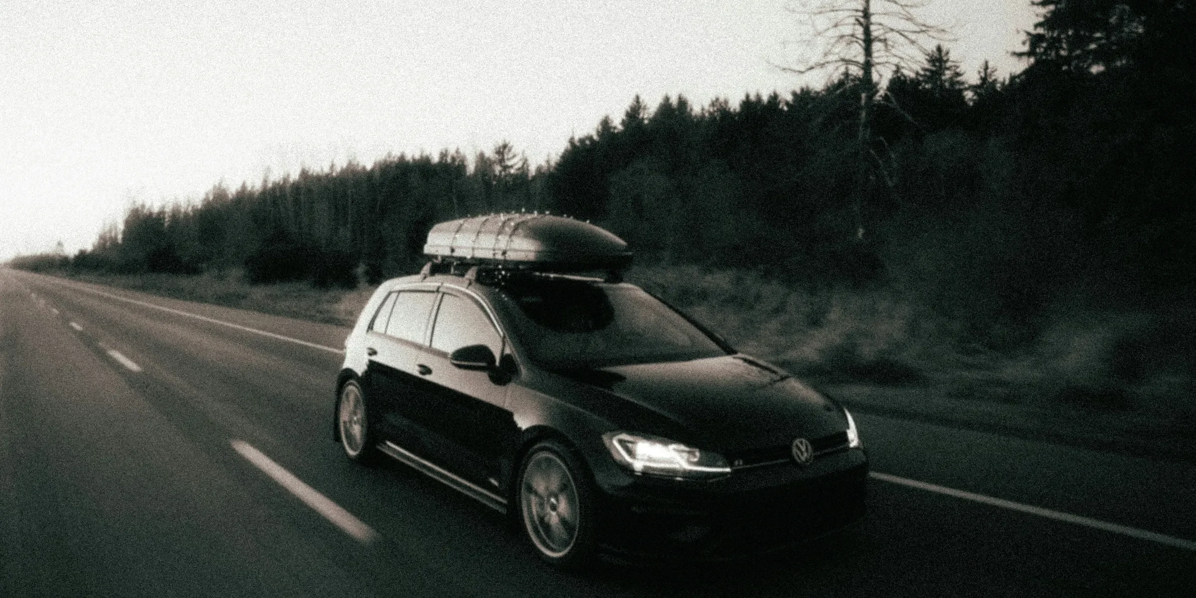 a car driving down a road with a surfboard on top of it